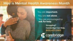 Poster with two women hugging indicating that May is Mental Health Awareness Month.  Call CareBridge for support at 800-437-0911.